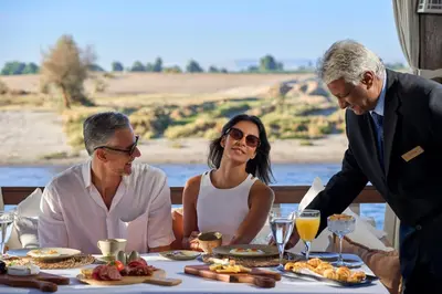 a group of people sitting around a table with food at HMC Musk Dahabyia in Luxor