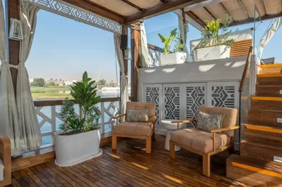 a balcony with two chairs and potted plants at HMC Musk Dahabyia in Luxor