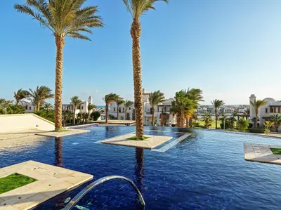 a swimming pool with palm trees in a resort at Ancient Sands Golf Resort and Residences in Hurghada