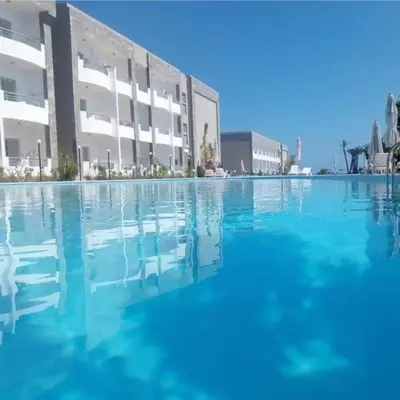 a pool of blue water in front of a building at cecelia resort in Hurghada