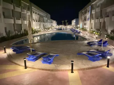 a swimming pool with blue lounge chairs in front of a building at cecelia resort in Hurghada