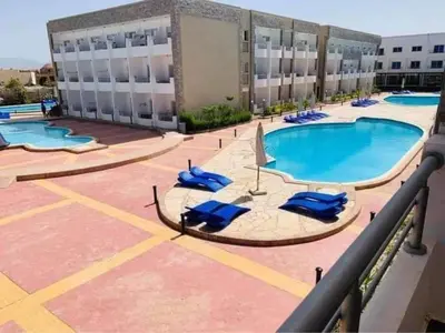 a pool on the roof of a building with blue lounge chairs at cecelia resort in Hurghada