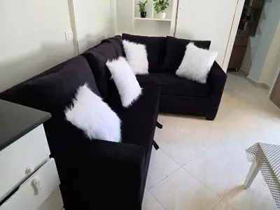 a black couch with white pillows on it at Do wynajęcia apartament w Hurghadzie w resorcie Aqua Tropical in Hurghada
