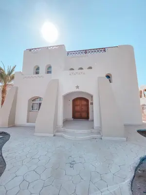 a large white building with a wooden door at Logement entier villa Marsa Alam, Égypte in Quseir