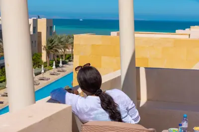 a woman sitting on a balcony looking out at the ocean at Hurgada El Gouna Mangroovy 1 bedroom with roof top in Hurghada