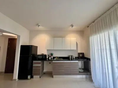 a kitchen with white cabinets and a black refrigerator at G-Cribs 1BR • Boho Pool Access in Hurghada