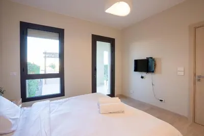 a bedroom with a white bed and a tv on the wall at Shedwan 2BR • Exquisite Ground Floor in Hurghada