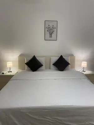a large white bed with black pillows and two lamps at Cozy 1 bedroom Apartment in Azzurra Sahl Hasheesh in Hurghada