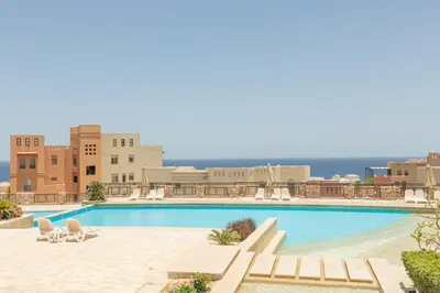a swimming pool with chairs and the ocean in the background at Spacious sea view ,1 bedroom apartment in Azzurra Sahl Hasheesh in Hurghada