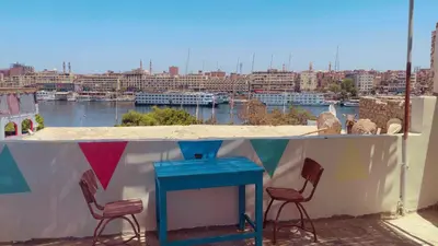 a table and chairs on a balcony with a view of a city at Wateen guest house in Aswan
