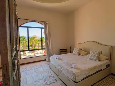 a bedroom with a bed and a large window at Super Central Somabay 2BR Marina Apt w Free Beach in Hurghada