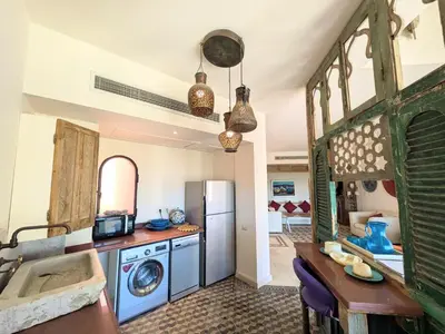 a kitchen with a refrigerator and a table and a sink at Super Central Somabay 2BR Marina Apt w Free Beach in Hurghada