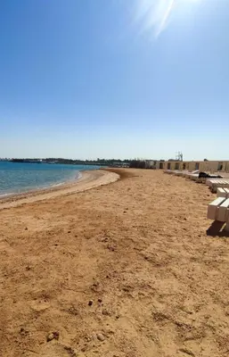 an empty beach with a bench on the shore at Princess Resort in Hurghada
