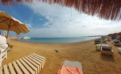 a beach with chairs and an umbrella and the ocean at Princess Resort in Hurghada
