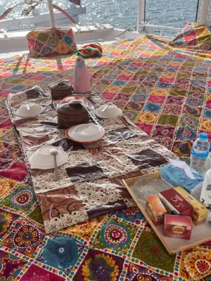 a table with plates and dishes on top of a quilt at Assuan Felucca in Aswan