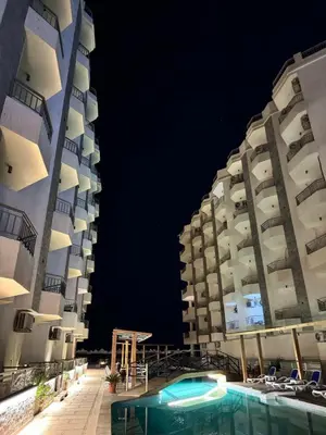 two tall buildings next to a swimming pool at night at La Quinta Hurghada Pool & Sea View Ground floor in Hurghada