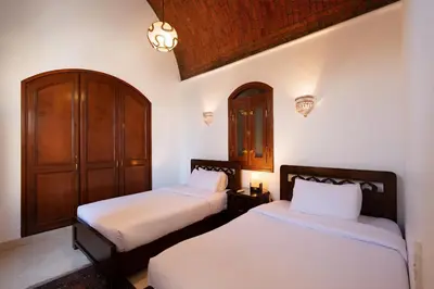 a bedroom with two beds and a wooden cabinet at Stylish Villas in North Golf El Gouna in Hurghada