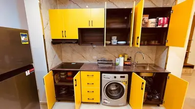 a kitchen with yellow cabinets and a washing machine at Modern apartment for rent in Hurghada