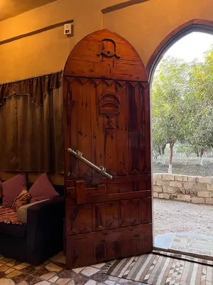 a wooden door with a face on it next to a bed at Villa Harmony Luxor in Luxor