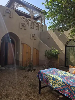 a bed sitting outside of a house with a building at Villa Harmony Luxor in Luxor