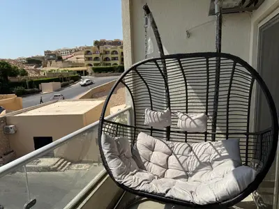 a swinging chair on a balcony with a street at Old Sheraton street apartment in Hurghada