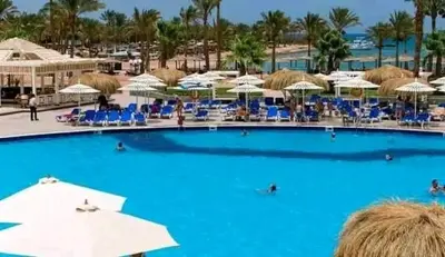 a large blue swimming pool with chairs and umbrellas at Mirage Bay Aqua Park Apartments in Hurghada
