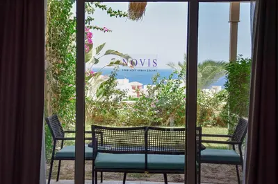 a view of the beach from a window with chairs at Novis Holiday Homes Sahl Hasheesh in Hurghada