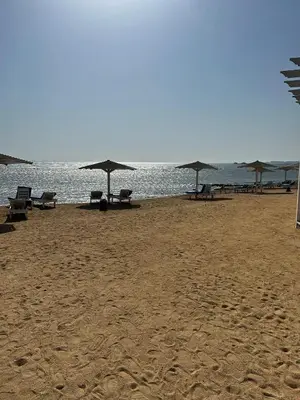 a beach with chairs and umbrellas on the sand at Luxury Apartment in Hurghada