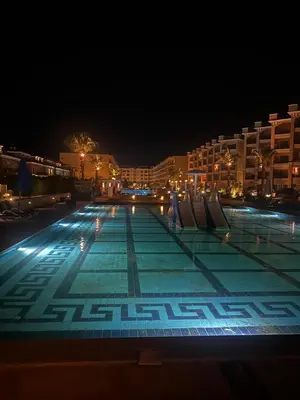 a large swimming pool at night with buildings at Luxury Apartment in Hurghada