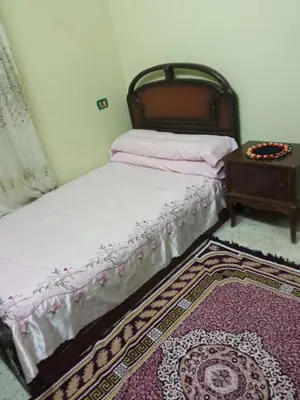 a bedroom with a bed with a table and a rug at هاي موود in Jazīrat Aswān
