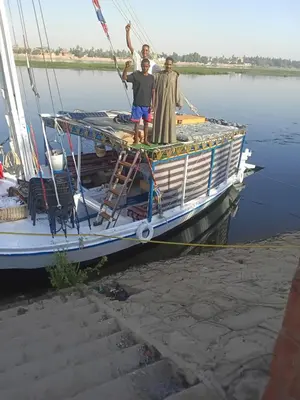 a group of three men standing on the deck of a boat at Felucca Alaska in Aswan