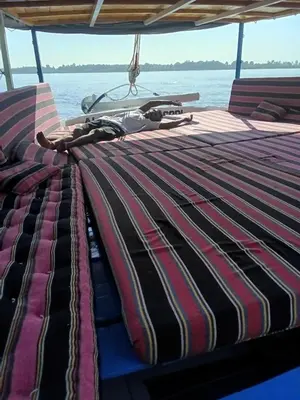 a boat with a striped blanket on the back of it at Felucca Alaska in Aswan