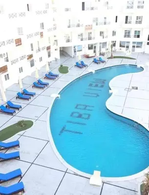 a large swimming pool with blue chairs and a building at Tiba view in Hurghada