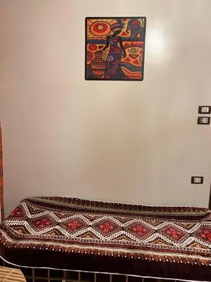 a painting hanging on a wall above a bed at Aswan House center in Aswan