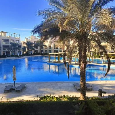 a large swimming pool with a palm tree and buildings at El-Gouna in Hurghada
