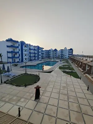 a woman in a dress standing in a courtyard with buildings at Oasis Resort Compound in Hurghada