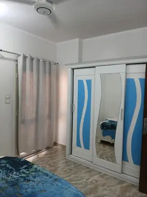 a bedroom with blue and white curtains and a bed at Essa Apartment in Safaga