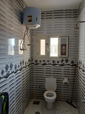 a bathroom with a white toilet and a window at Essa Apartment in Safaga