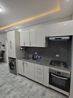 a kitchen with white cabinets and a stove top oven at Oasis marina الاحياء in Hurghada