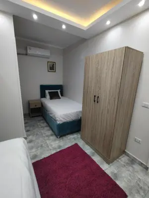 a small bedroom with a bed and a wooden door at Oasis marina الاحياء in Hurghada