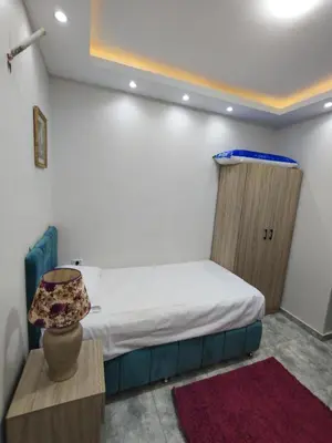 a bedroom with a bed and a table with a lamp at Oasis marina الاحياء in Hurghada