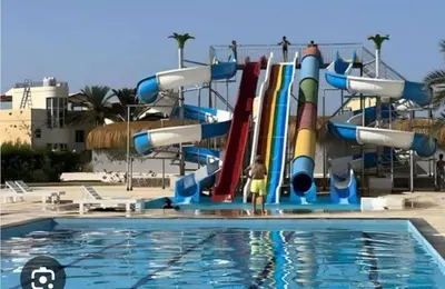 a person standing in front of a water slide in a pool at Fanadir bay resort in Hurghada