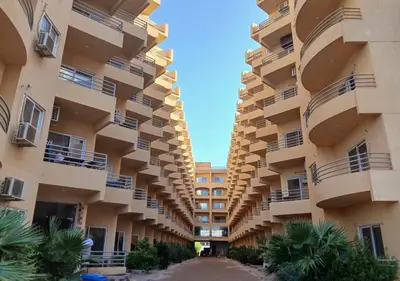 a large apartment building with balconies and palm trees at Fiesta Beach Resort in Hurghada