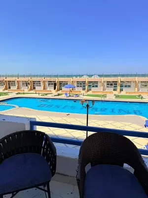 a balcony with two chairs and a swimming pool at شقة فندقية صف أول بحر وبول in Hurghada