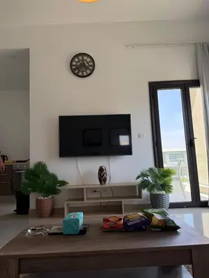 a living room with a table and a tv on the wall at Cozy 2BR with pool access in Hurghada