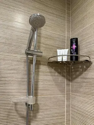 a shower head on a wall with a shelf in a bathroom at Cozy 2BR with pool access in Hurghada