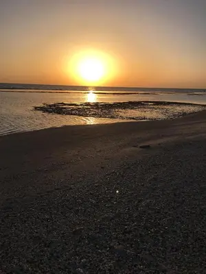 a sunset on a beach with the sun setting at Casa De Amor in Abu Dabab