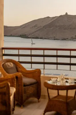 a balcony with a table and chairs and a view of the water at Aswan Heritage Residence-Nile View and Free Airport Pickup in Aswan