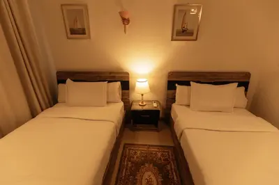 two beds in a room with a lamp on a table at Aswan Heritage Residence-Nile View and Free Airport Pickup in Aswan