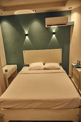 a bedroom with a white bed with a green wall at Town Hotel- Hurghada in Hurghada